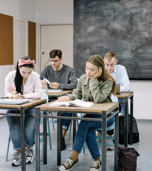 A group of teenagers focusing on studies in a classroom with a blackboard.